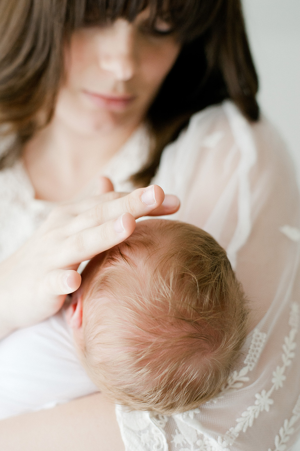 mother gently strokes her baby forehead as photographer captures the moment